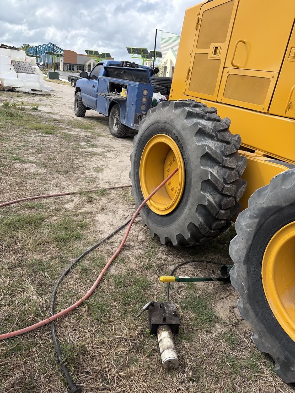 Motor grader tire repair at a construction site with mobile service truck